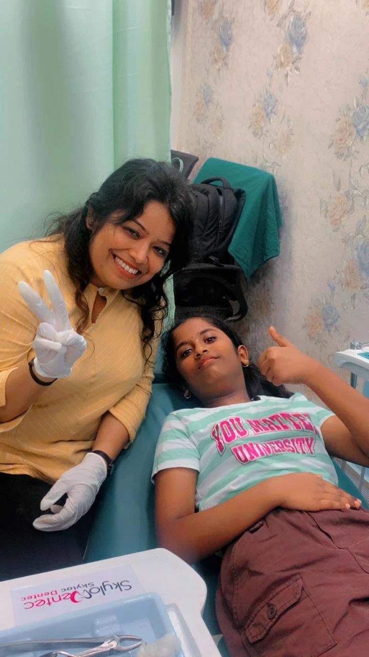A dentist and young visitor beside the dental chair
