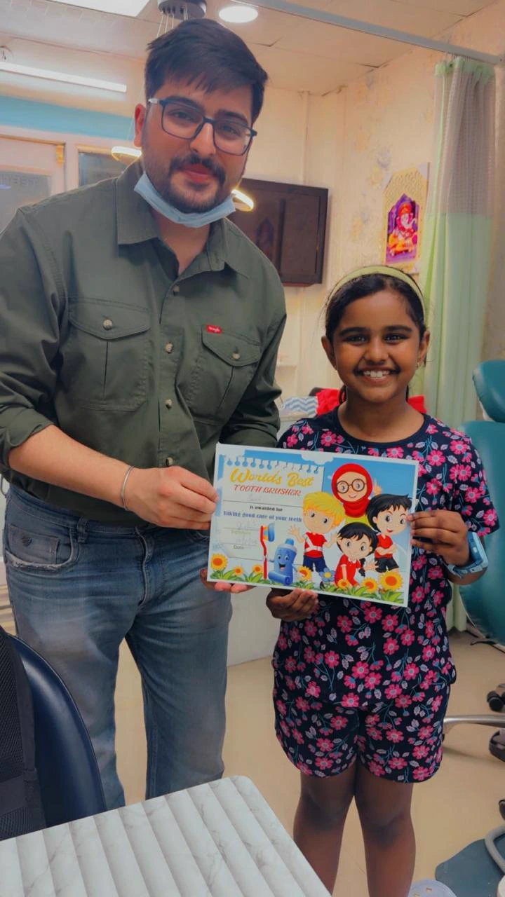 A dentist with a young visitor holding a tooth-brushing certificate