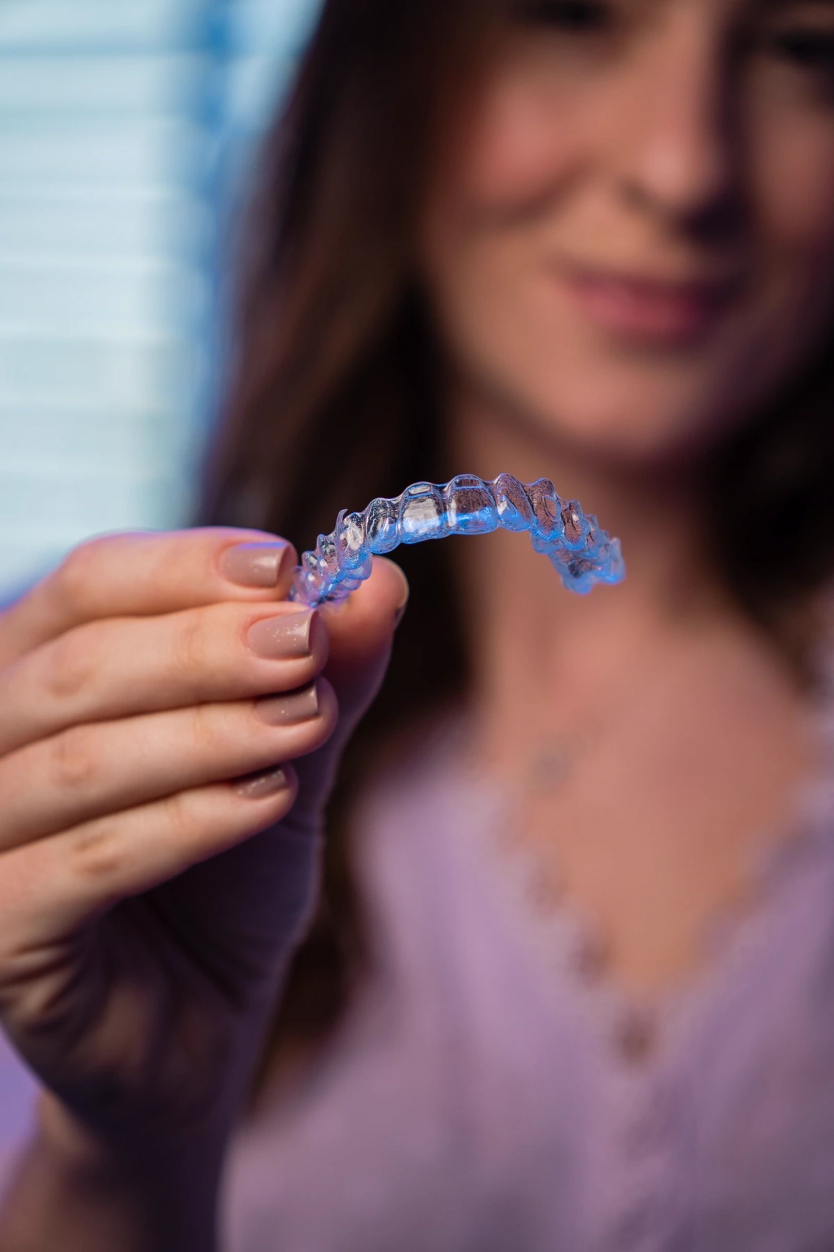 A clear dental aligner held for inspection